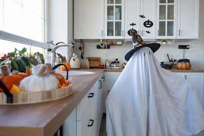 Blog Halloween-themed kitchen with ghost figure and festive pumpkins.